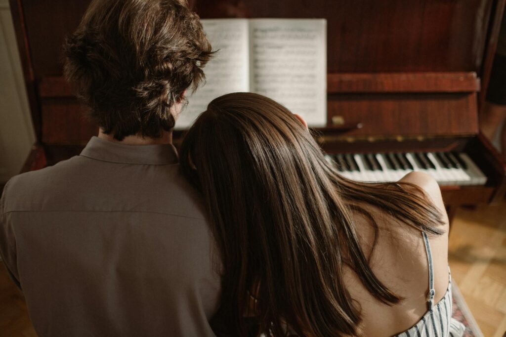 back view of a man and woman playing piano